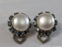 Front view of MCM style costume earrings showing faux pearl centers surrounded by rhinestones and heart charm below