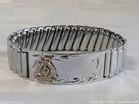 Front view of polished silver-tone expandable metal bracelet with RCMP badge emblem on plate showing 'Royal Canadian Mounted Police' and 'Canada'.