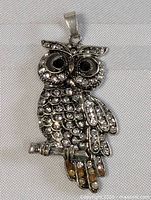 Close-up front view of owl pendant showing rhinestones and wear on talons