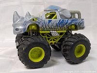 Side front view of the Rhino Monster Truck toy showing large tires and rhino horn details on vehicle body.
