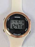 Close-up front view of Shhors digital wrist watch face showing time, date, and buttons.