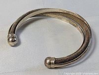 Solid sterling silver cuff bracelet shown from an angled side view highlighting the texture and form.