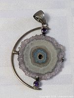 Full view of pendant showing geode cross section with amethyst crystals and sterling silver frame with purple amethyst stones.