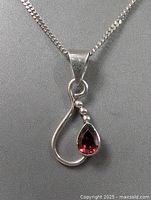Close-up of the sterling silver pendant with pear-shaped garnet stone and silver bead accents