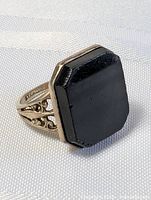 Close up front view of sterling silver ring with square-cut black onyx stone, showing the stone and detail of silver band.