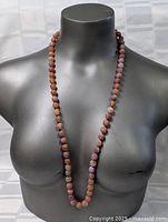 Full length of the necklace shown on torso mannequin to display length and color variation