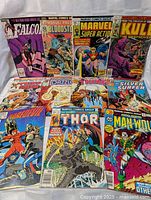 Photo of 11 vintage Marvel comics showing their front covers arranged in two rows. Titles include Falcon, Bloodstone, Marvel Super Action, Kull the Destroyer, Man-Thing, Dazzler, The Thing, Silver Surfer, Thor, and Man-Wolf.