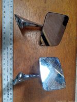 Pair of vintage 1970's Chevrolet side mirrors showing reflective surfaces and chrome arms measured against a ruler for size context.
