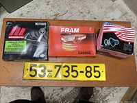 All items together on a wooden surface showing the air filters, electric horn box, and yellow license plate.