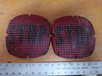 Two vintage red stop tail light lenses side by side on a wooden surface with a ruler below showing about 4.5 inch width each.