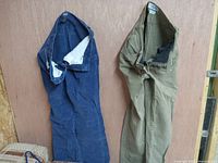 Two pairs of women's jeans pants, one blue denim and one olive green, shown hanging open to reveal interior details.