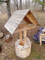 Side view of the wishing well showing roof and base structure in outdoor setting.
