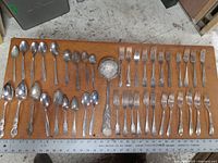 Overview of all spoons and forks spread on a wooden surface with a ruler for scale