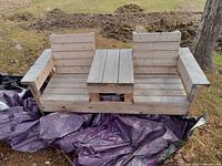 Front view of the double seat bench with center table, showing two seats with vertical slat backs and a horizontal slat center table, made from spruce lumber.