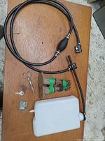 All items arranged on a wooden surface showing the fuel hose, washer container, plow shoes, keys, scissors, and small metal part.