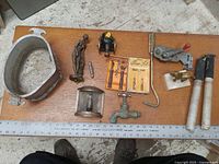 Top-down view of mixed antique items arranged on wooden surface showing various tools, mold, statue, and hardware pieces.