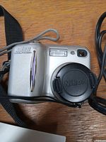 Front view of Nikon Coolpix 885 with lens cap on and wrist strap