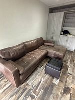 L-shaped sectional sofa, ottoman and glass-top cube table positioned in corner of room