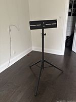 Black metal tripod TV or monitor stand with adjustable height and mounting bracket