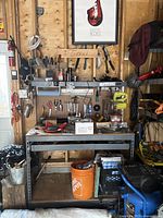 Front view of metal workbench loaded with tools against pegboard wall