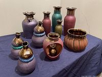 Photo showing all ten decorative clay pots and vases in various shapes and colors including purple, turquoise, and gold metallic finishes.