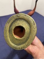 Close-up of unglazed bottom showing rough clay texture and circular hollow base of one bird sculpture