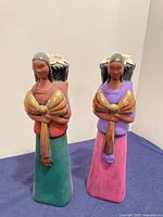 Two colorful folk art Mexican clay figurines side by side, showing front and partial side detail
