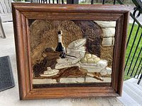 Front view of medium-sized embossed metal art depicting Mexican still life with food items and a bottle, framed in wood.