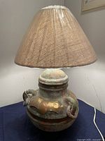 Full view of the rustic textured clay lamp base paired with conical burlap lamp shade.