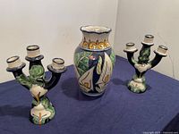Photo showing three Talavera ceramic candle holders surrounding a floral vase, all handpainted in vibrant blue, green, white, and yellow with calla lily motifs.
