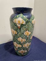 Front view of Talavera ceramic vase showing detailed calla lily pattern with green leaves and dark blue top