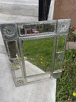 Front view of the rectangular wall mirror showing pressed tin frame with intricate floral and geometric embossed patterns and mirrored panels.