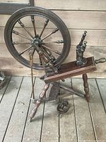 Full view of antique wooden spinning wheel showing legs, drive wheel, table and flyer assembly