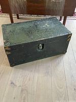 Overall view of closed green metal footlocker trunk