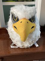 Front view of white faux-fur eagle mascot head showing beak and eyes