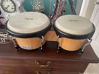 Front view of bongo pair showing wood shells, black rims, mounting block and tuning lugs