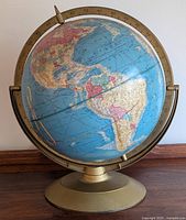 Front view of the 12-inch globe showing North and South America, supported with brass-colored metal mounting and circular base.