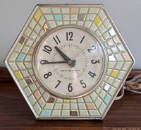 Front view of the hexagonal General Electric clock showing pastel mosaic tile design and clock face with black numbers.