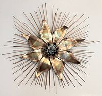 Full view of the Curtis Jere style Brutalist starburst sculpture against a white wall showing the sculpture's radial pattern and metal textures.