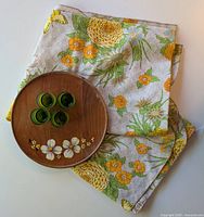 Vintage floral tablecloth with wooden tray and four green shot glasses arranged on it