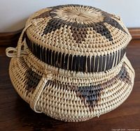 Side view of the hand-woven basket showing the geometric woven patterns and lid with latch.