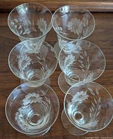 Top view of six clear etched parfait glasses showing floral cornflower designs on the bowls.