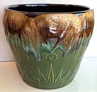 Front angled view of the large Roseville Moon and Stars pottery planter showing green base with brown glossy glaze dripping down.