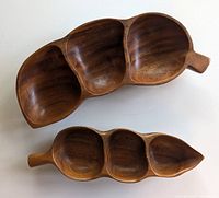 Two monkey pod serving dishes viewed from above showing three compartments each and wood grain details.