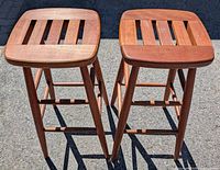 Top view of two wooden barstools showing square slatted seats with four slats each.