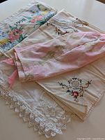 Four linen pieces displayed, showing their floral and embroidered designs, color tones, and lace features.