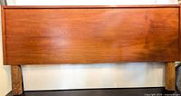 Full front view of the teak queen headboard on attached wooden legs