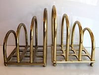 Side view of the two brass letter holders showing their rounded arch dividers and grid bases.