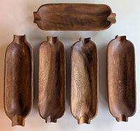 Five wooden trays shaped like corn ears shown laid flat to display carved handles and wood grain.