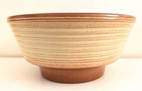 Side view of the West German pottery planter showing the textured beige exterior with horizontal ridges and brown glazed rim.